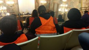 Bild aus Stadtratssitzung. Zuschauer in orangenen Westen