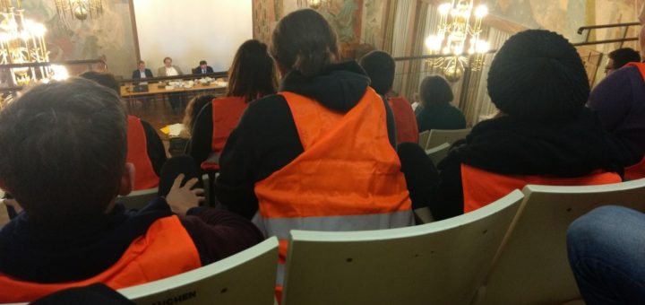 Bild aus Stadtratssitzung. Zuschauer in orangenen Westen